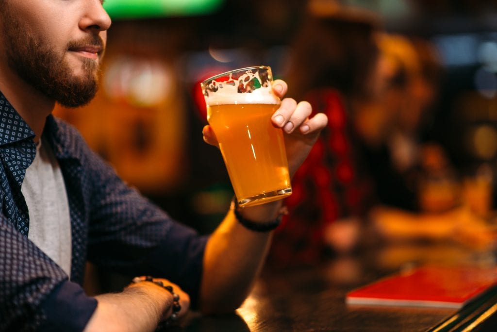 Man drinks beer at the bar counter in a sport pub